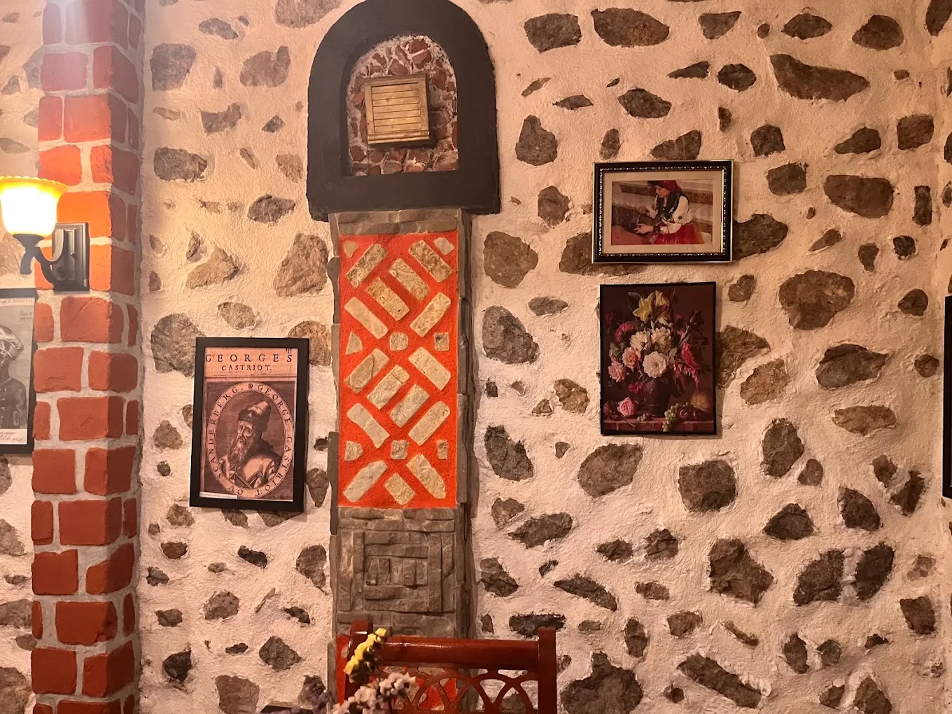 Terracotta geometric decoration and framed pictures on Tradita’s stone wall.