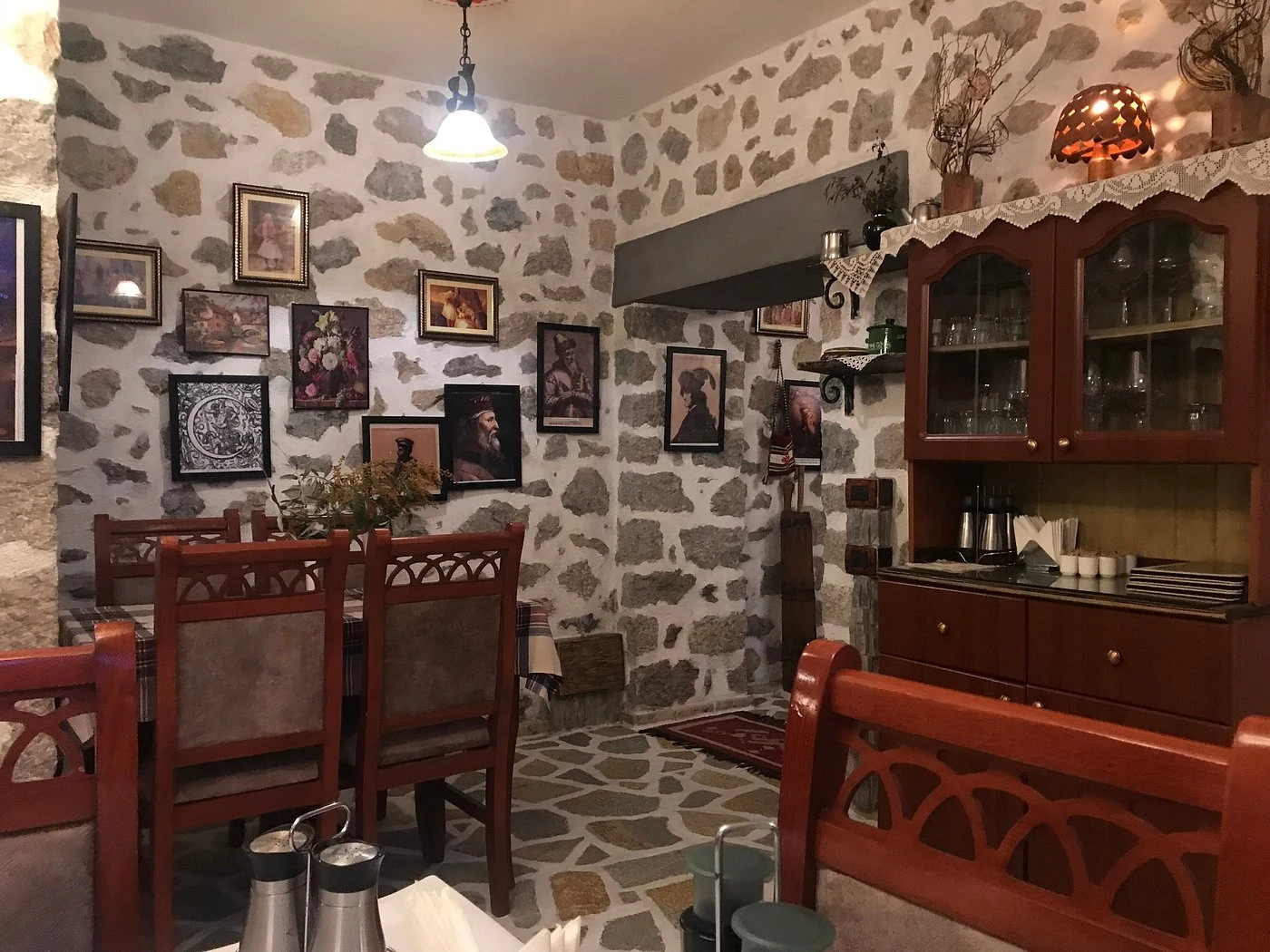 Carved wooden chairs, framed pictures and warm lamps in Tradita’s dining room.